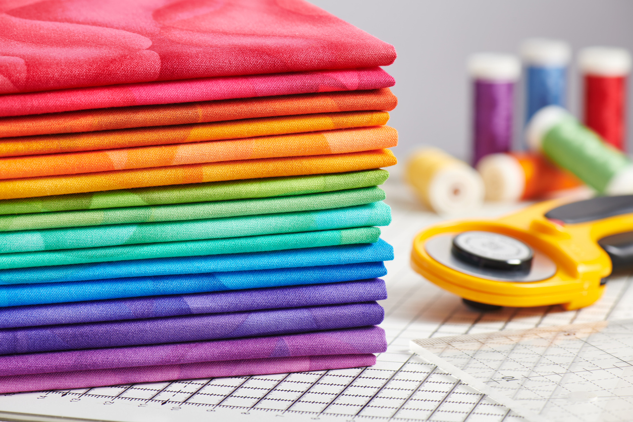 Stack of bright multicolored fabrics, accessories for sewing and quilting